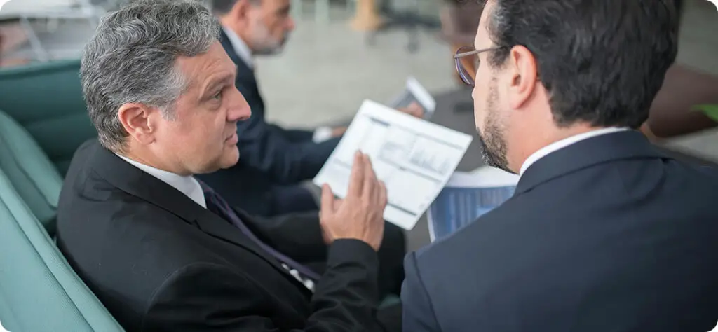 A financial advisor explaining charts and investment options to a couple, illustrating variable life insurance benefits